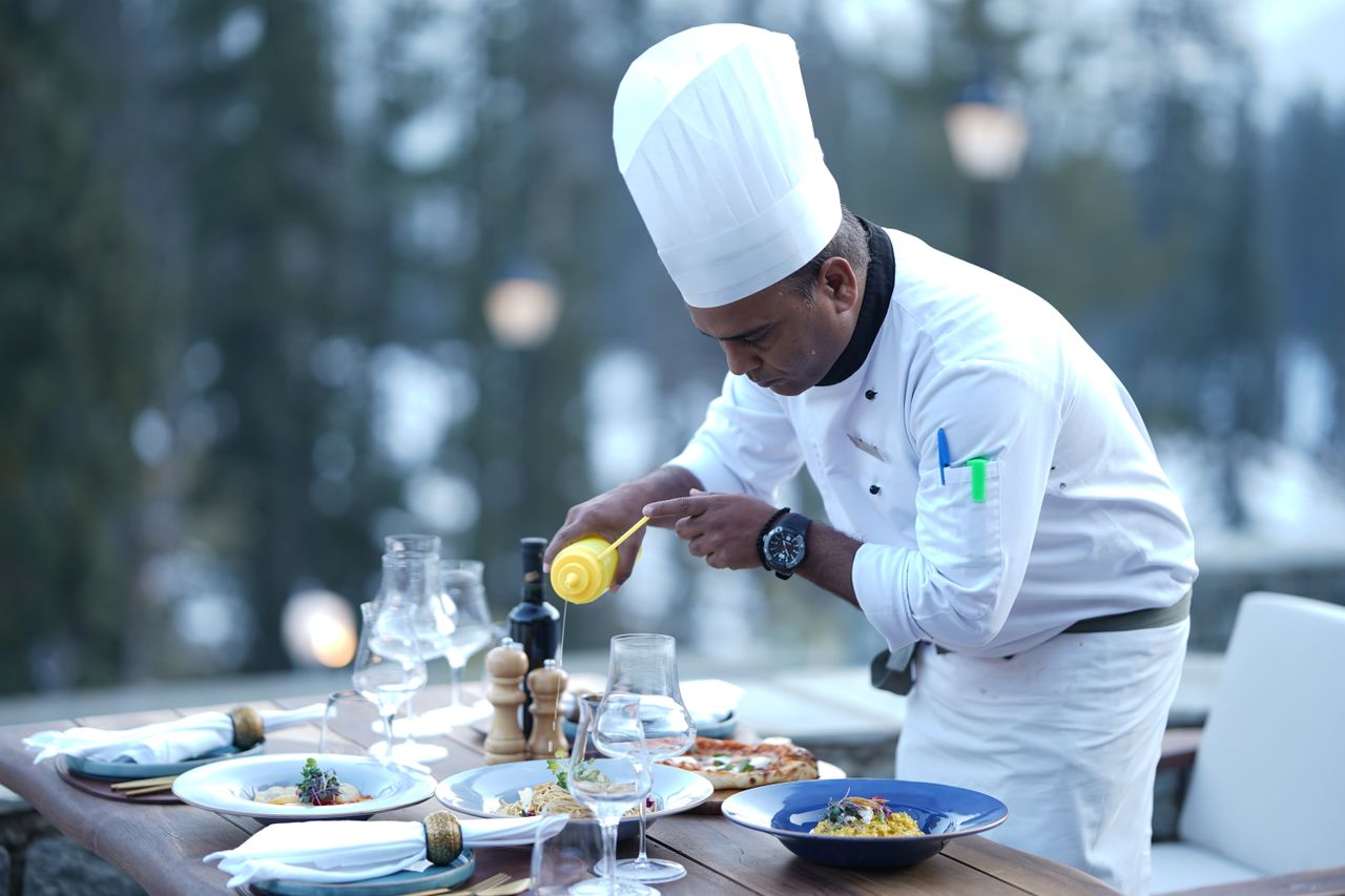 Menus A chef skillfully prepares dishes for a stunning outdoor dining experience, showcasing food artistry.