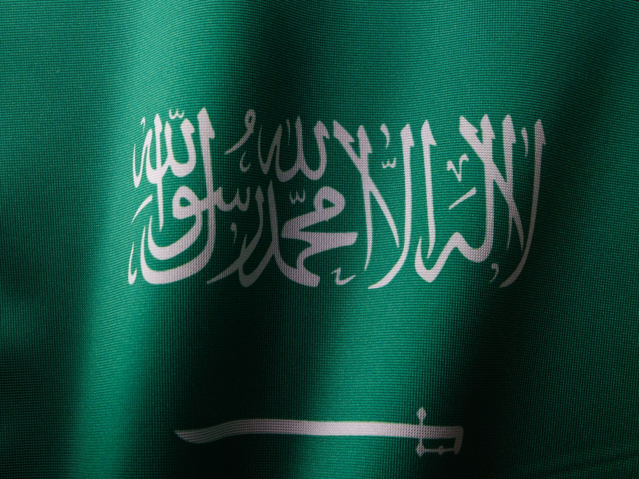 The Art of Drawing Readers In: Your attractive post title goes here Detailed close-up of the Saudi Arabian flag showcasing the elegant Arabic script and vibrant green color.