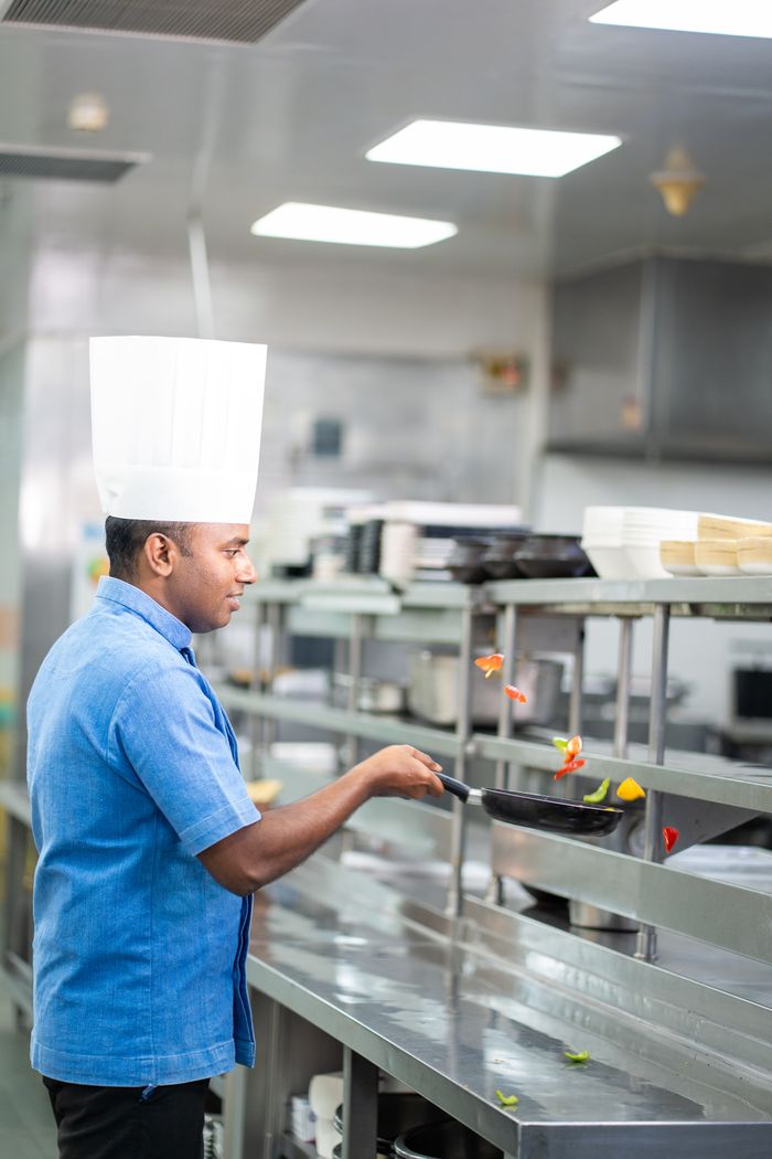 Menus Chef skillfully cooking vegetables in a modern restaurant kitchen, emphasizing culinary expertise.