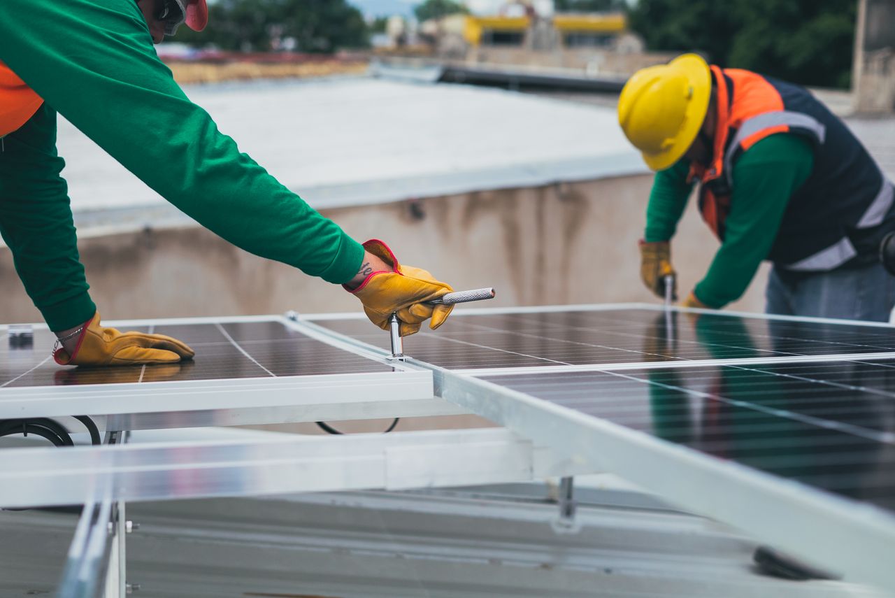 Home Workers secure solar panels on a rooftop, advancing renewable energy.